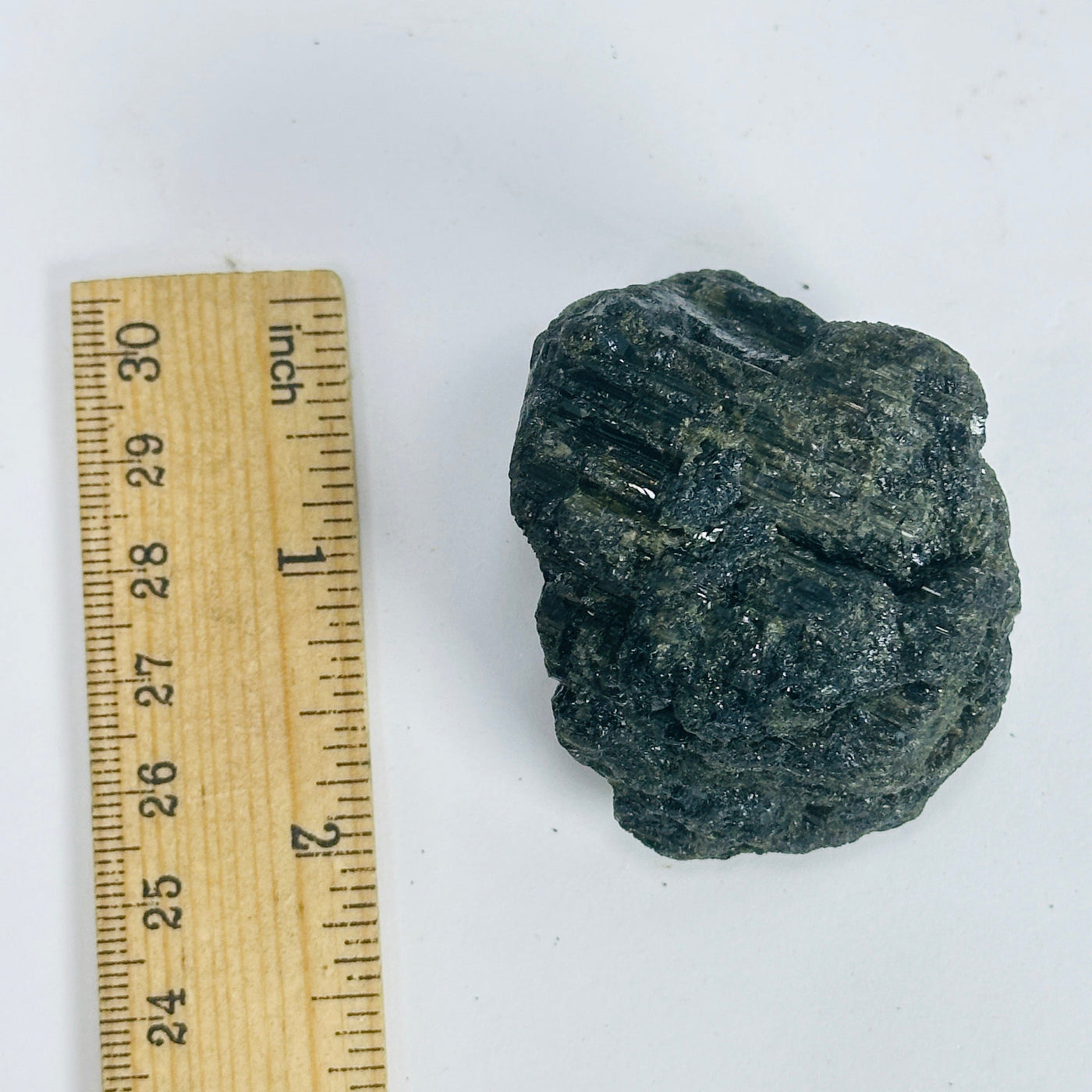 green tourmaline next to a ruler for size reference