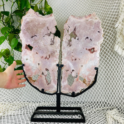 hand next to Pink amethyst wings with decorations in the background