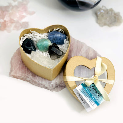 growth heart box opened revealing hematite, amazonite, smoky quartz, clear quartz, and blue lace agate with crystals in the background