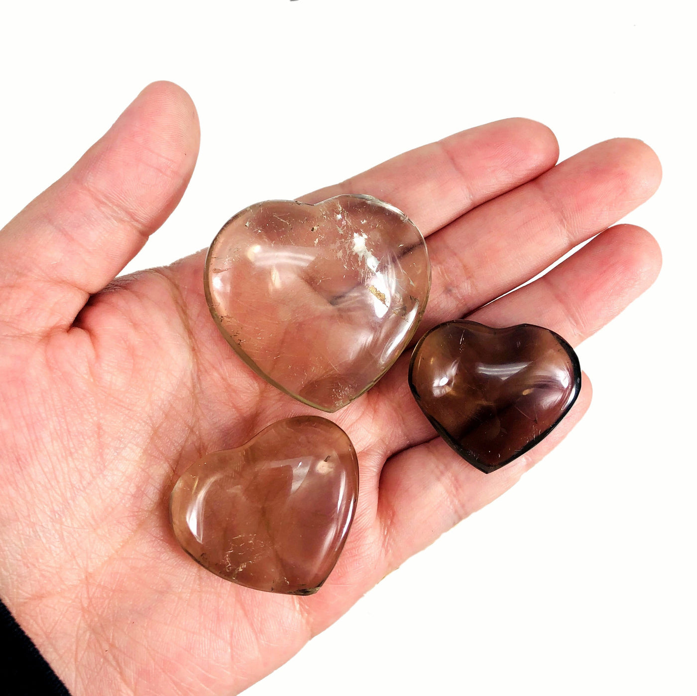 3 Smokey Quartz Polished Hearts on a hand to show size reference 