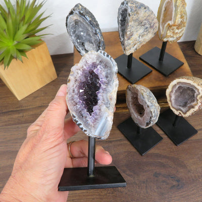 hand holding up geode on metal stand with others in the background