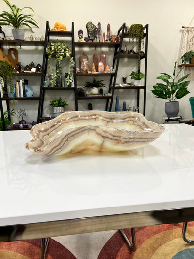 Mexican onyx bowl in shades of cream, tan, brown and white displayed on a counter top.