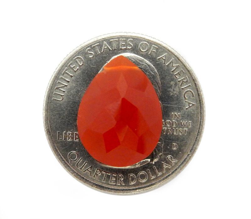 Red Onyx  Briolette on top of quarter for size reference on white background