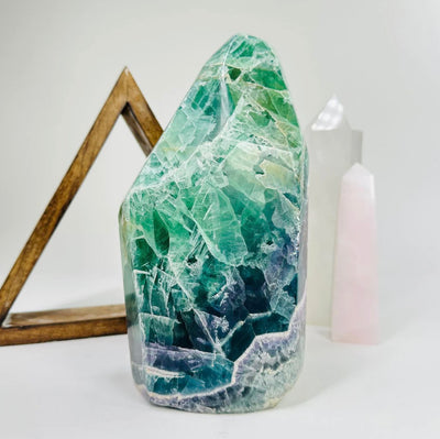 colorful rock in front of other crystals and a wooden triangle