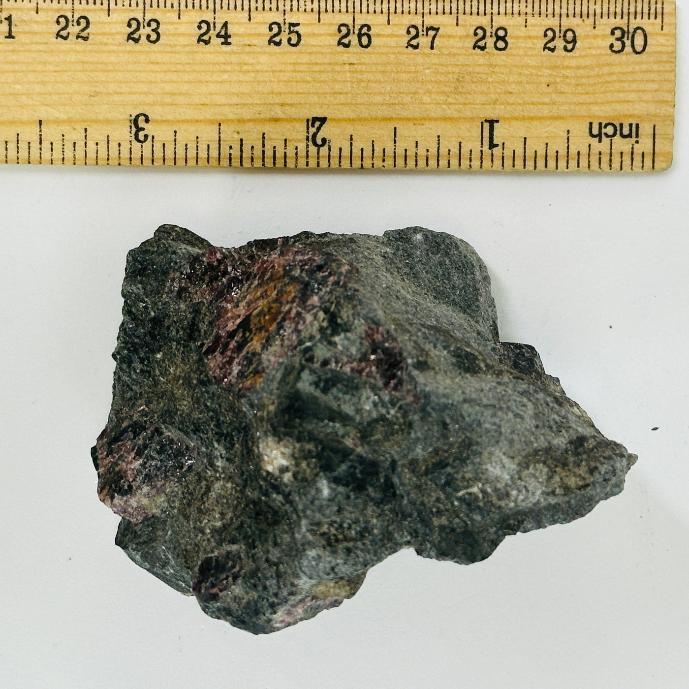 garnet on hematite next to a ruler for size reference