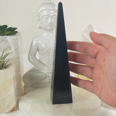 Silver Sheen Obsidian Crystal Obelisk - One-of-a-Kind #2 with hand for size reference with props and plants in the background