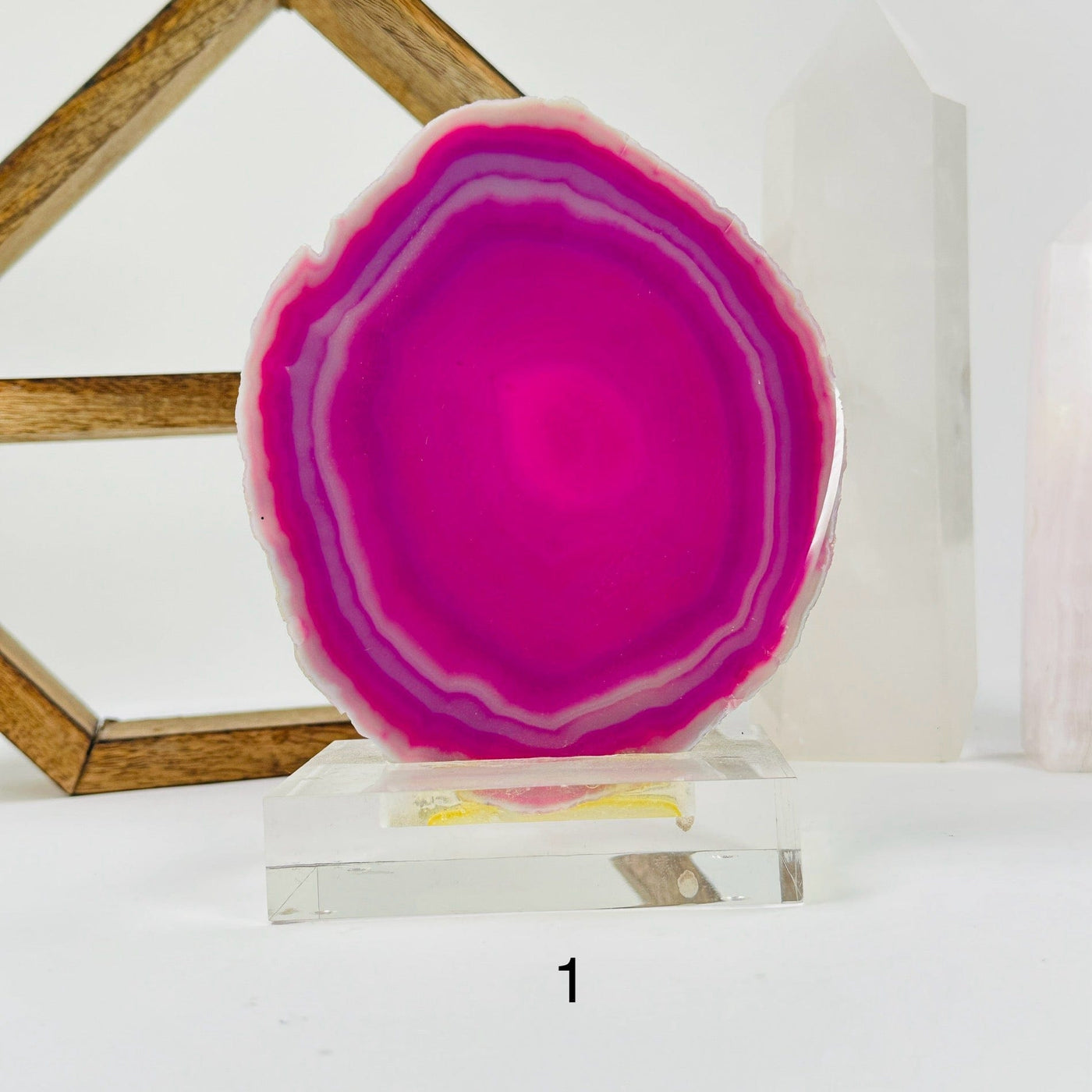 pink agate slice on acrylic stand with decorations in the background