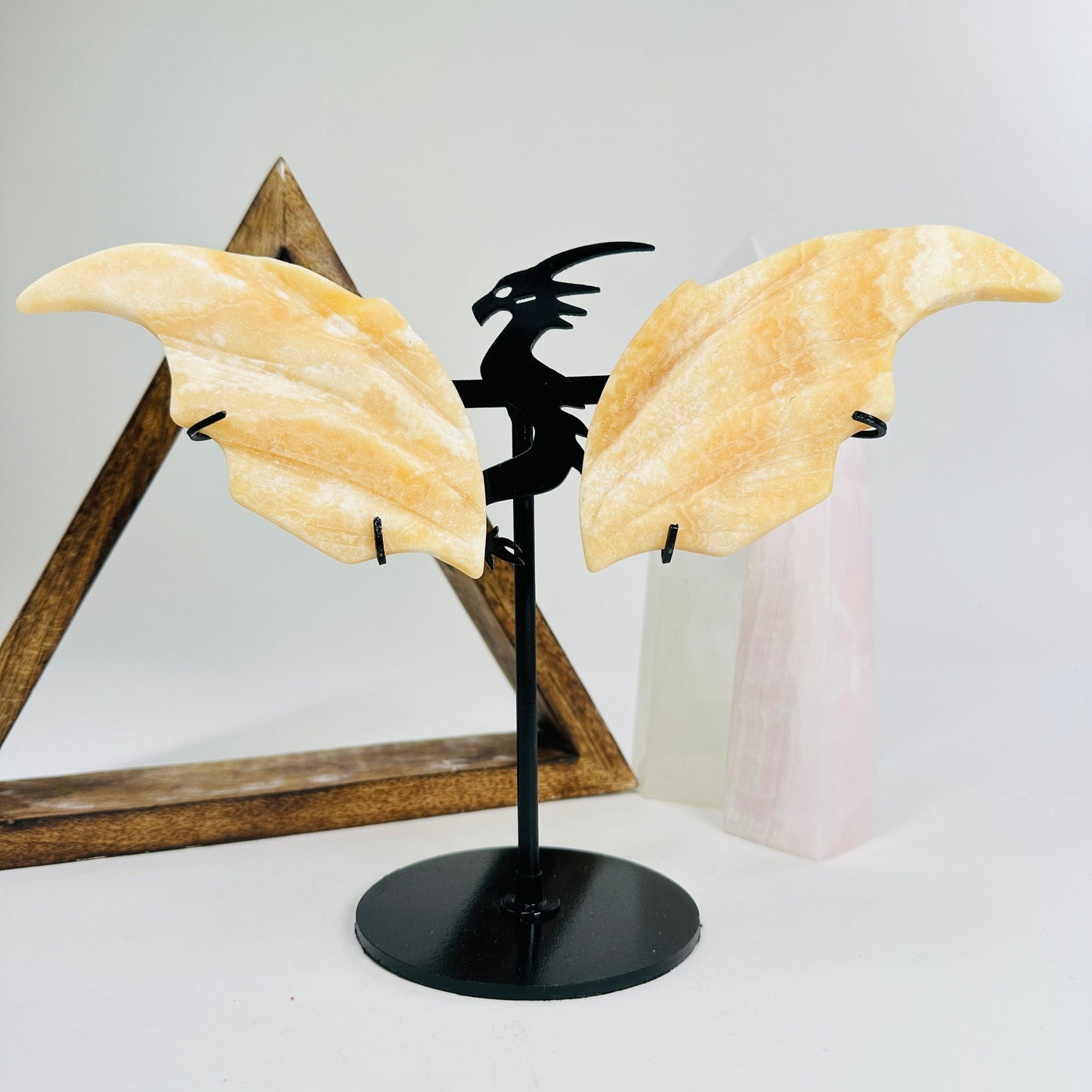 orange calcite dragon on metal stand with decorations in the background