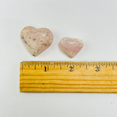 pink opal hearts next to a ruler for size reference