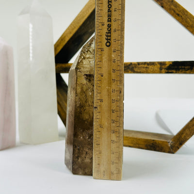 smokey quartz point next to a ruler for size reference