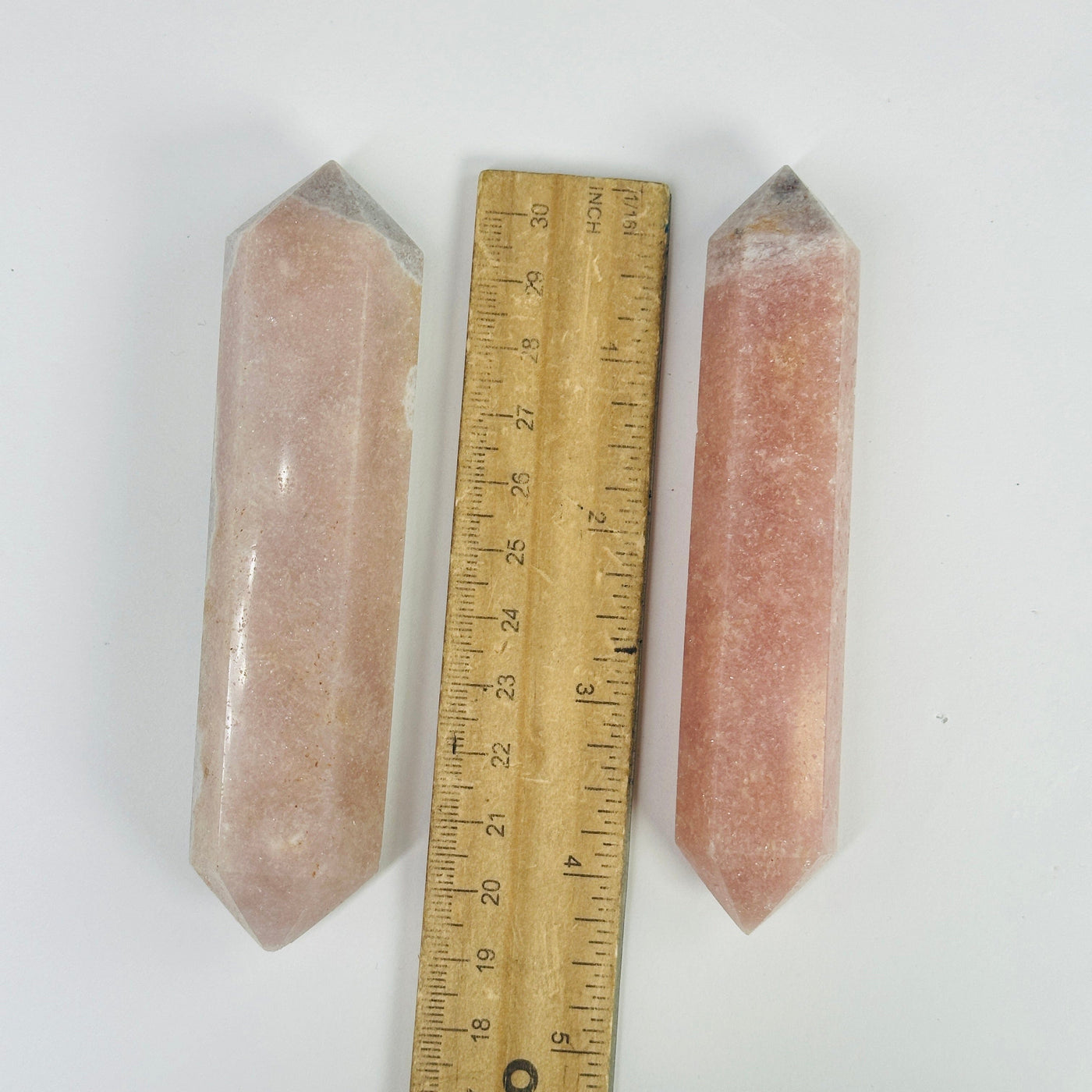 pink amethyst points next to a ruler for size reference