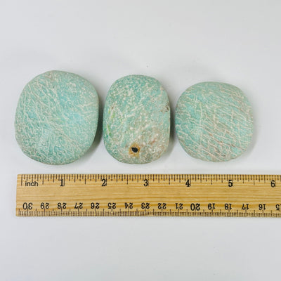 amazonite tumbled stones next to a ruler for size reference