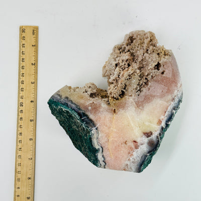 pink amethyst cluster next to a ruler for size reference