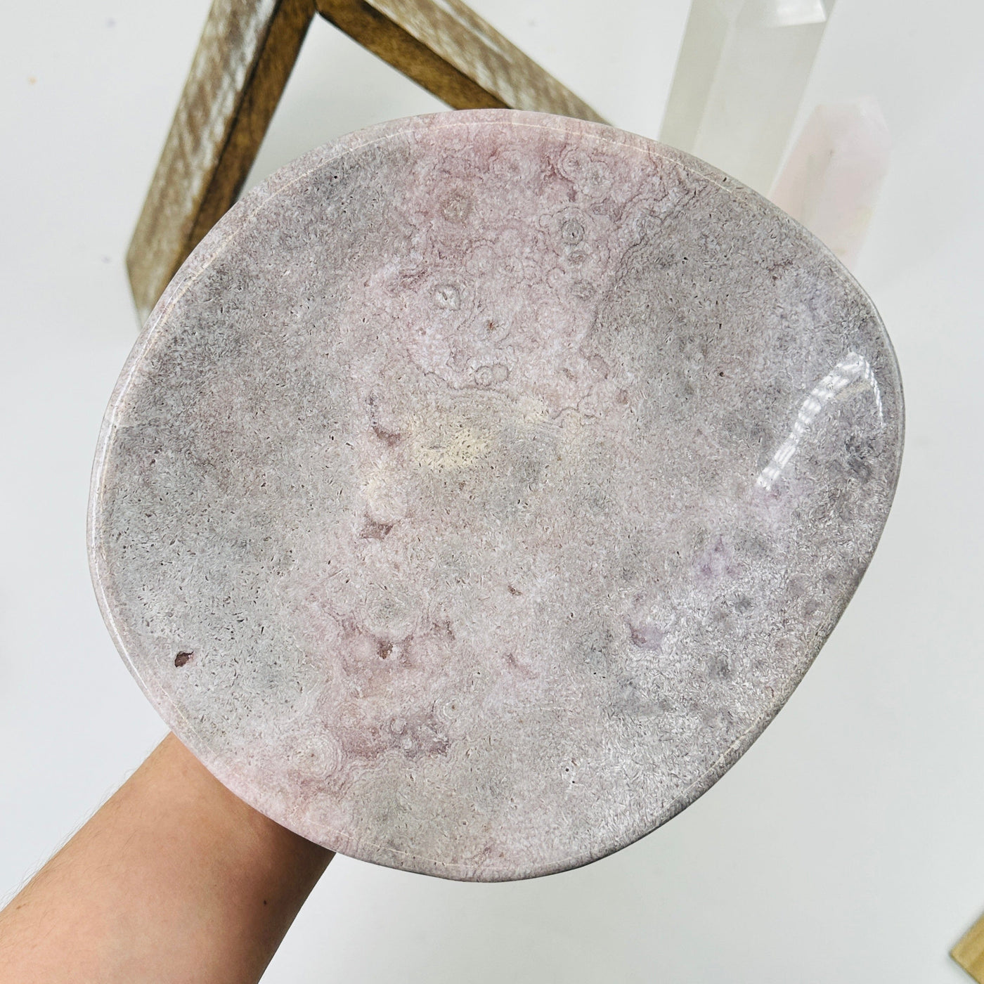 hand holding up pink amethyst plate with decorations in the background