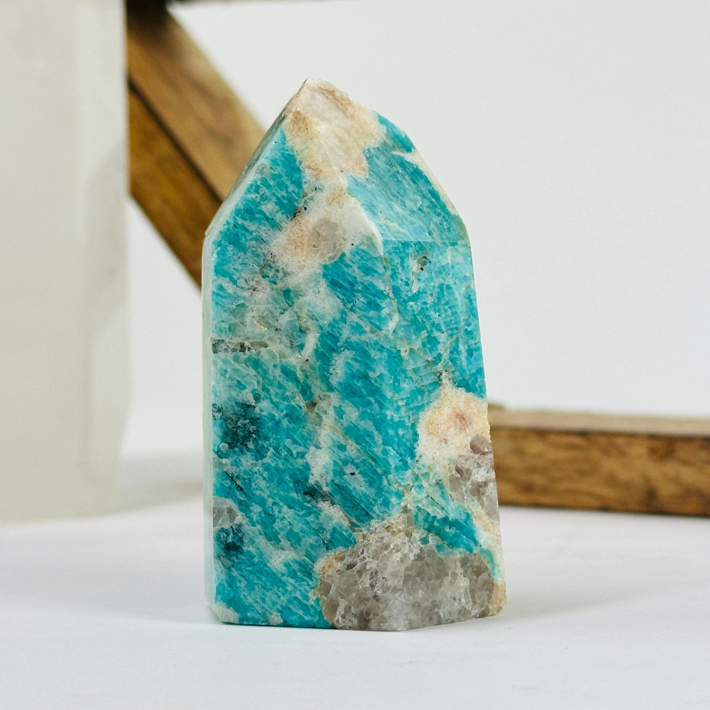Amazonite polished point with decorations in the background