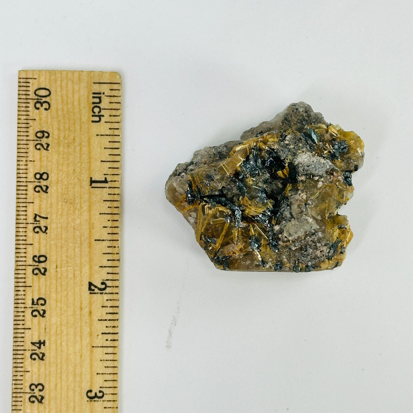 rutilated quartz next to a ruler for size reference