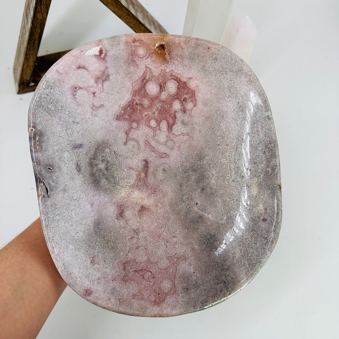 hand holding up pink amethyst bowl with decorations in the background