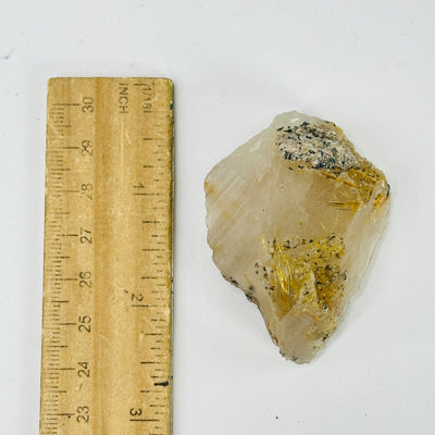 rutilated quartz next to a ruler for size reference