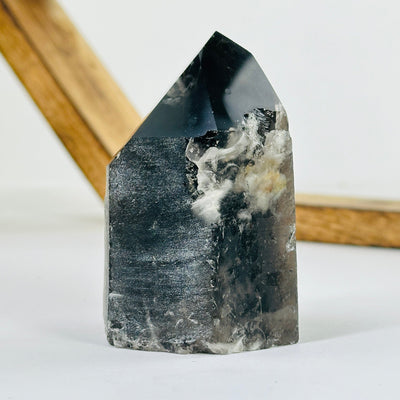 smokey quartz polished point with decorations in the background