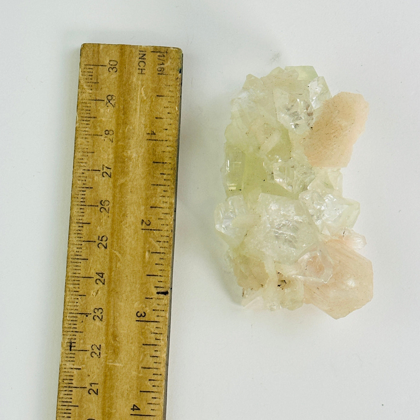  peach apophyllite with stilbite cluster next to a ruler for size reference