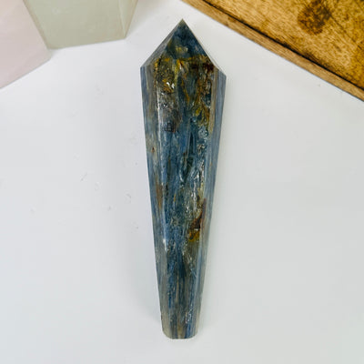 kyanite point with decorations in the background