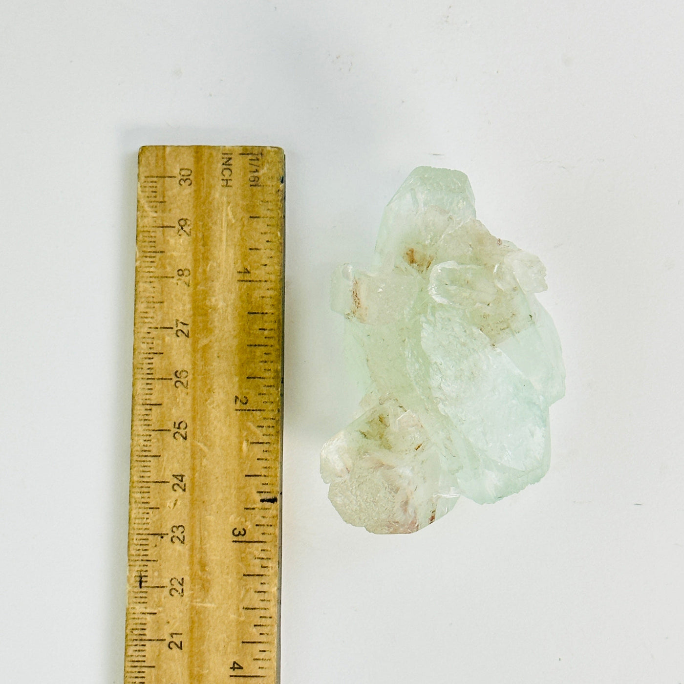 green apophyllite with stilbite cluster next to a ruler for size reference