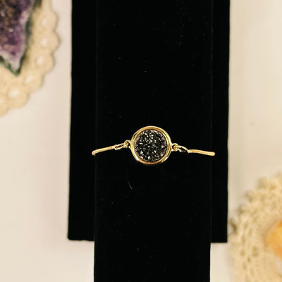 black diamond druzy gold snake chain bracelet with decorations in the background