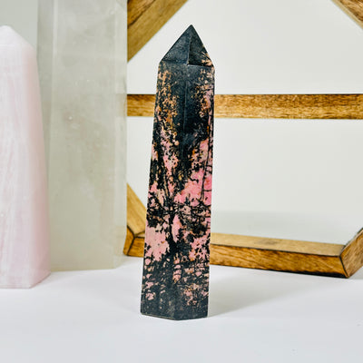 rhodonite point with decorations in the background