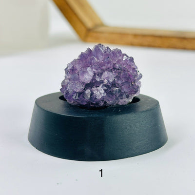 amethyst cluster on stand with decorations in the background