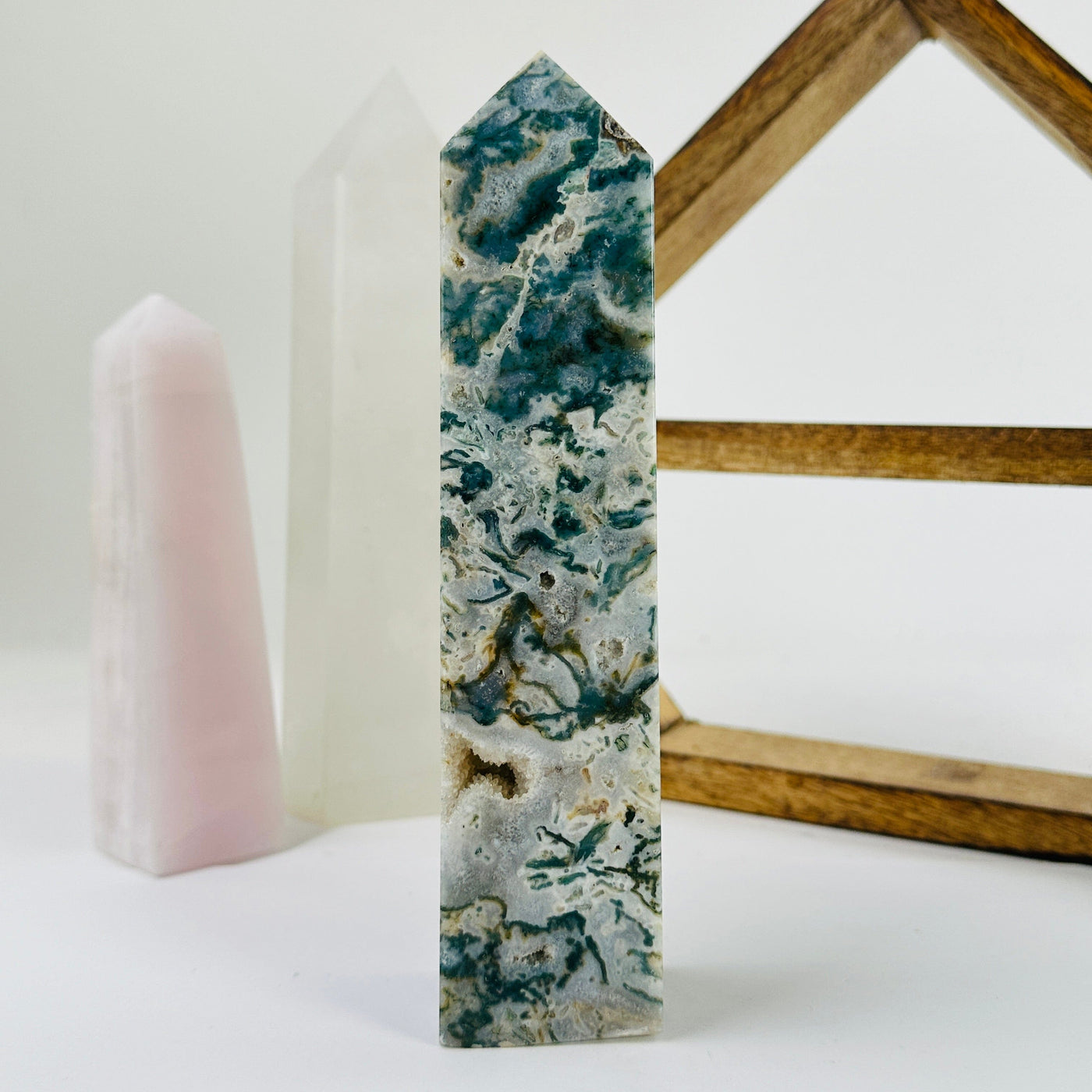 moss agate polished point with decorations in the background