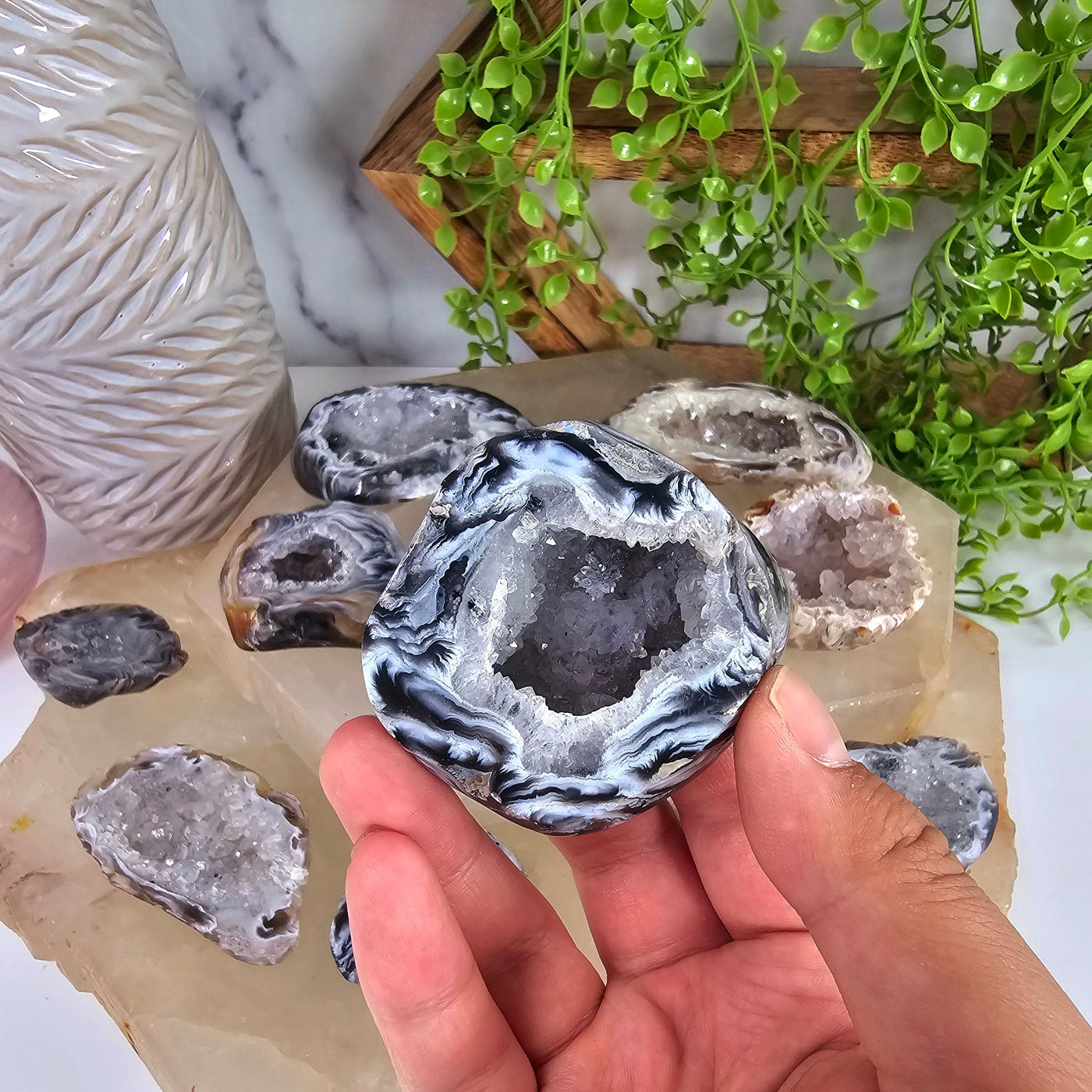 Agate Geode Half - Occo Agate Crystal Geode - You Choose variant 7 in hand with other variants in the background for size reference