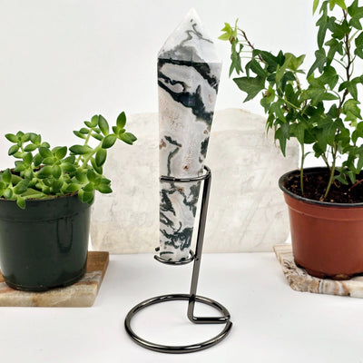 Moss Agate Wand on Stand 2 side view with plants and props in the background