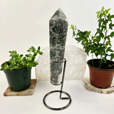 Moss Agate Wand on Stand 3 side view with plants and props in the background