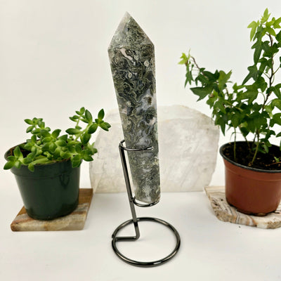 Moss Agate Wand on Stand 3 side view with plants and props in the background