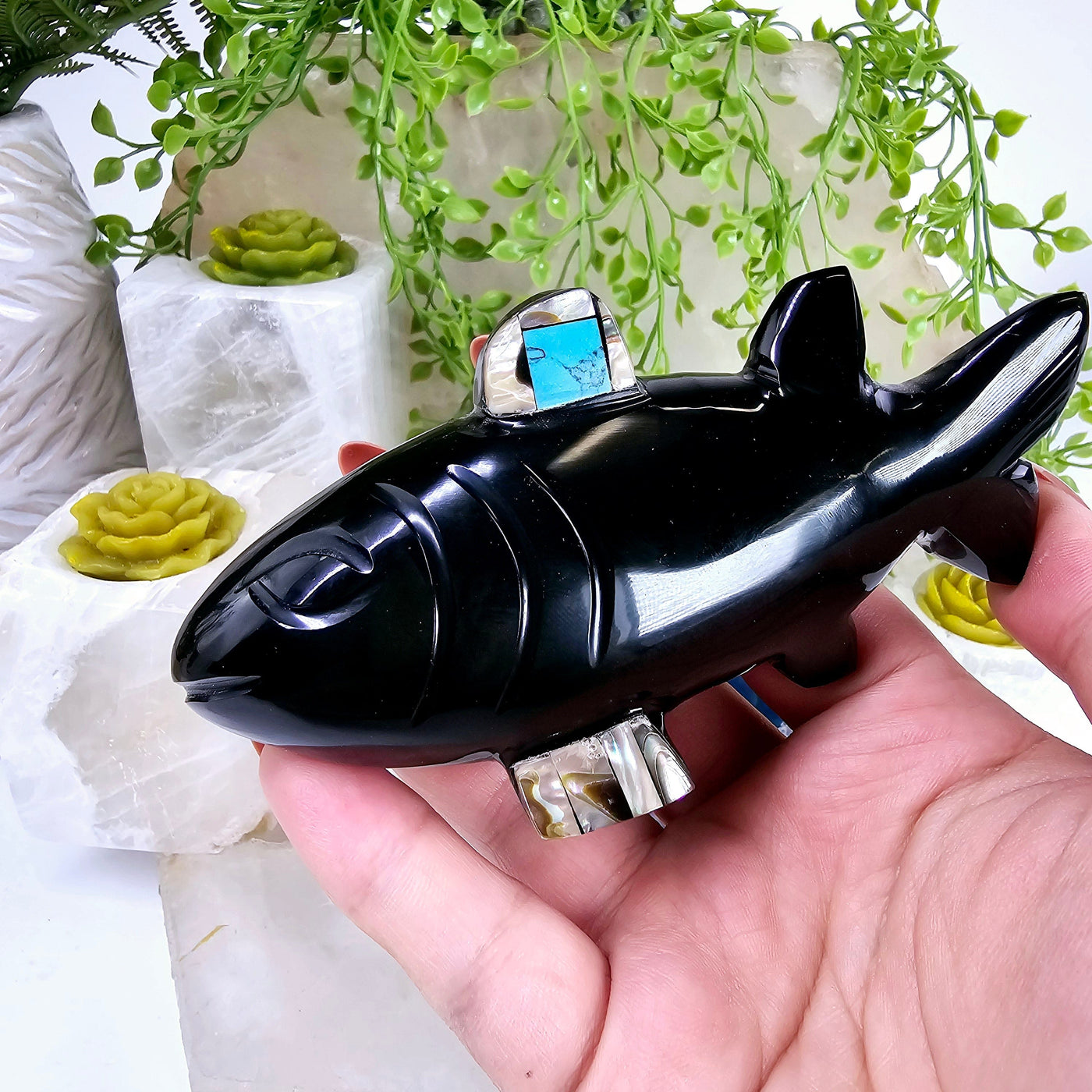 Black Onyx Fish with Shell and Gemstone Inlays in hand for size reference with props and plants in the background