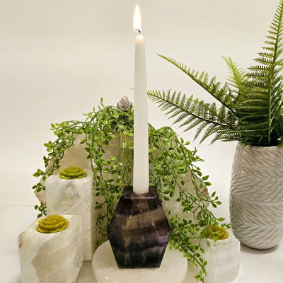 Fluorite Candle Holder with lit candle inside and props and plants in the background