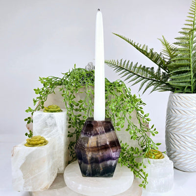 Fluorite Candle Holder with unlit candle inside with props and plants in the background