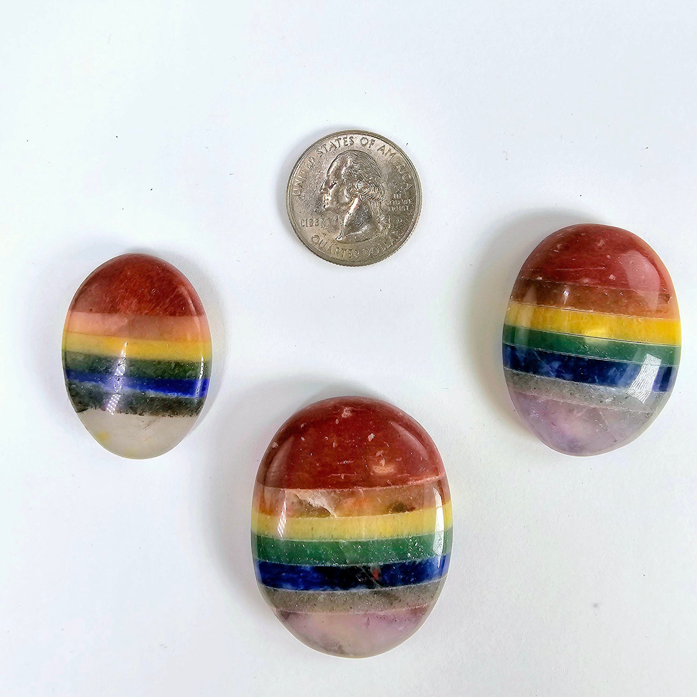 Seven Chakra Worry Stone three stones of varying sizes next to quarter for size reference