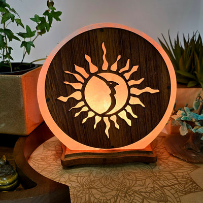 Large Sun and Moon Himalayan Salt Lamp - As Is - lit in dim lighting with plants and props in the background