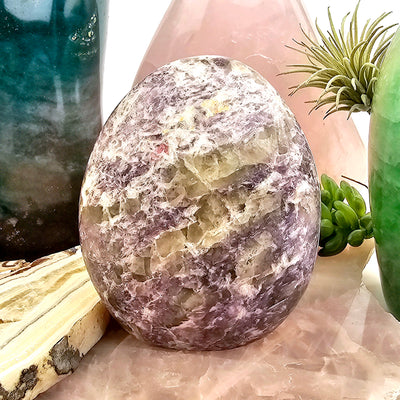 Lepidolite Cut Base #2 front view with props and plants in the background