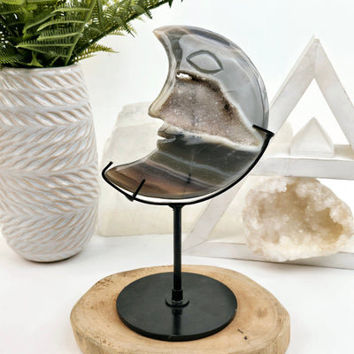 Agate Crystal Moon Carving on Metal Stand front view with props in the background