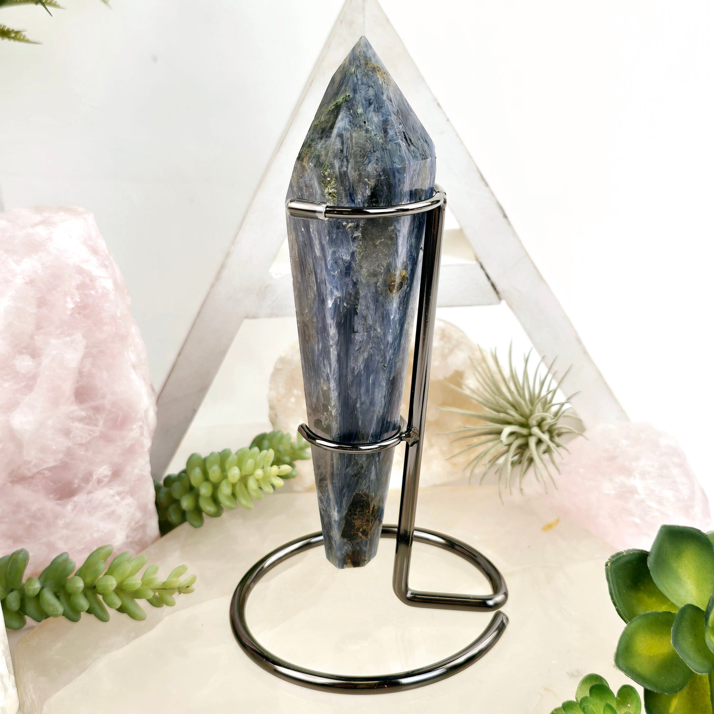 Blue Kyanite Crystal Wand on Stand #3 side view with plants and props in the background