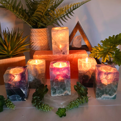 Fluorite Crystal Candle Holder - AA Grade candles lit in each one with plants and props in the background