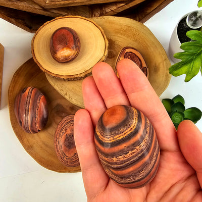 Wave Dolomite Palm Stone - You Choose variant C in hand for size reference with other variants in the background on wooden platters