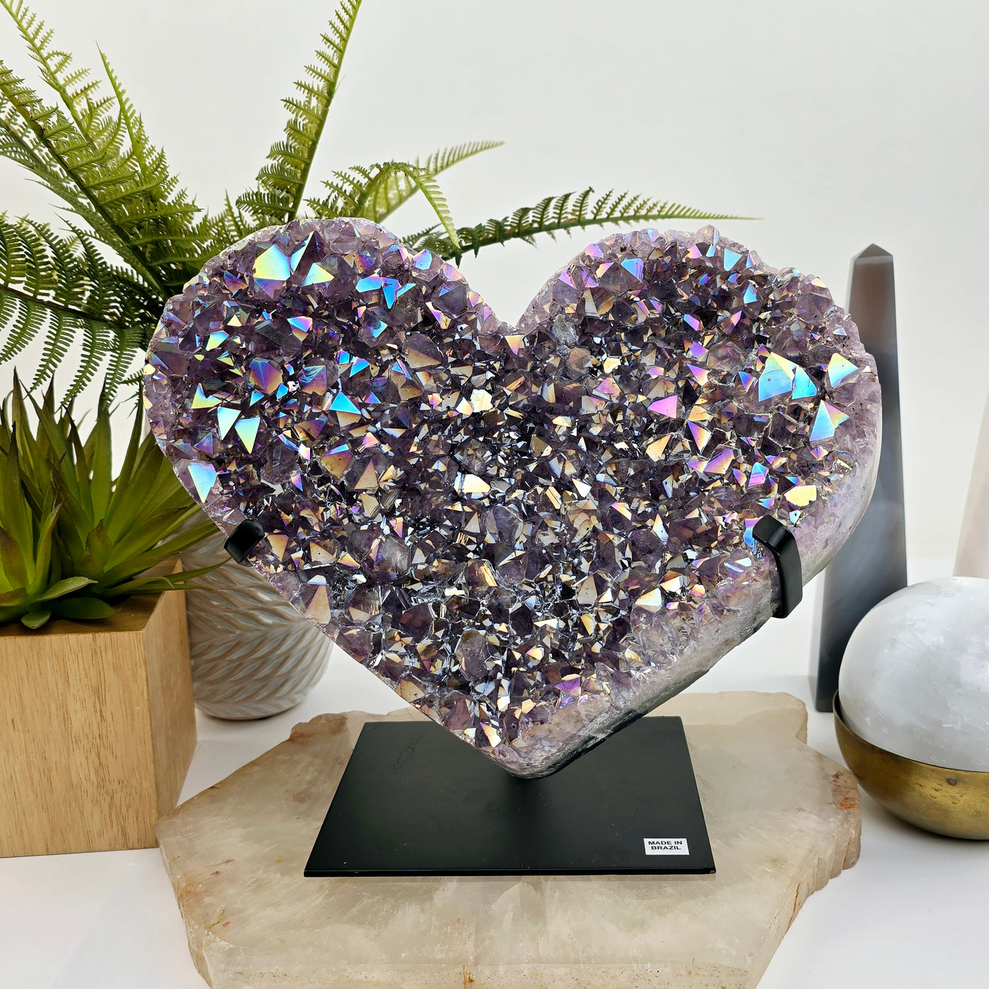 Angel Aura Amethyst Crystal Heart on Metal Stand on quartz platter with props and plants in the background front view