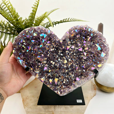 Angel Aura Amethyst Crystal Heart on Metal Stand with hand for size reference