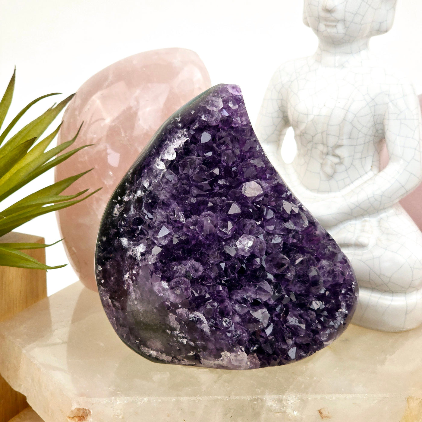 Amethyst and Agate Teardrop Crystal Cut Base on quartz platter with props and plants in the background front view