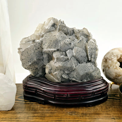 Calcite and Stibnite Crystal Cluster with Wooden Stand front view with props in the background