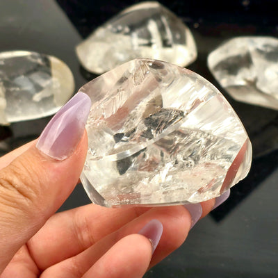 Polished Crystal Quartz Lens with Manifestations - You Choose - variant 4 in hand for size reference with other variants in the background