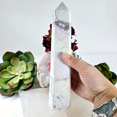 White Howlite Aura Crystal Obelisk #2 - in hand for size reference with plants and props in the background